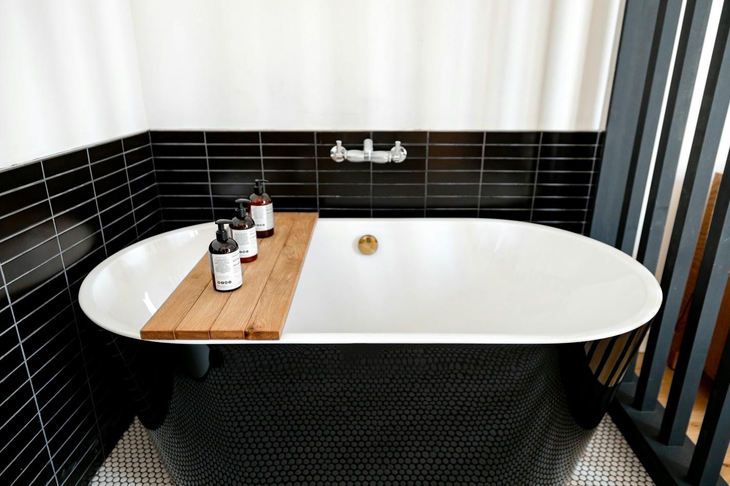 An image of a bathtub with a wooden plank on it holding bottles.