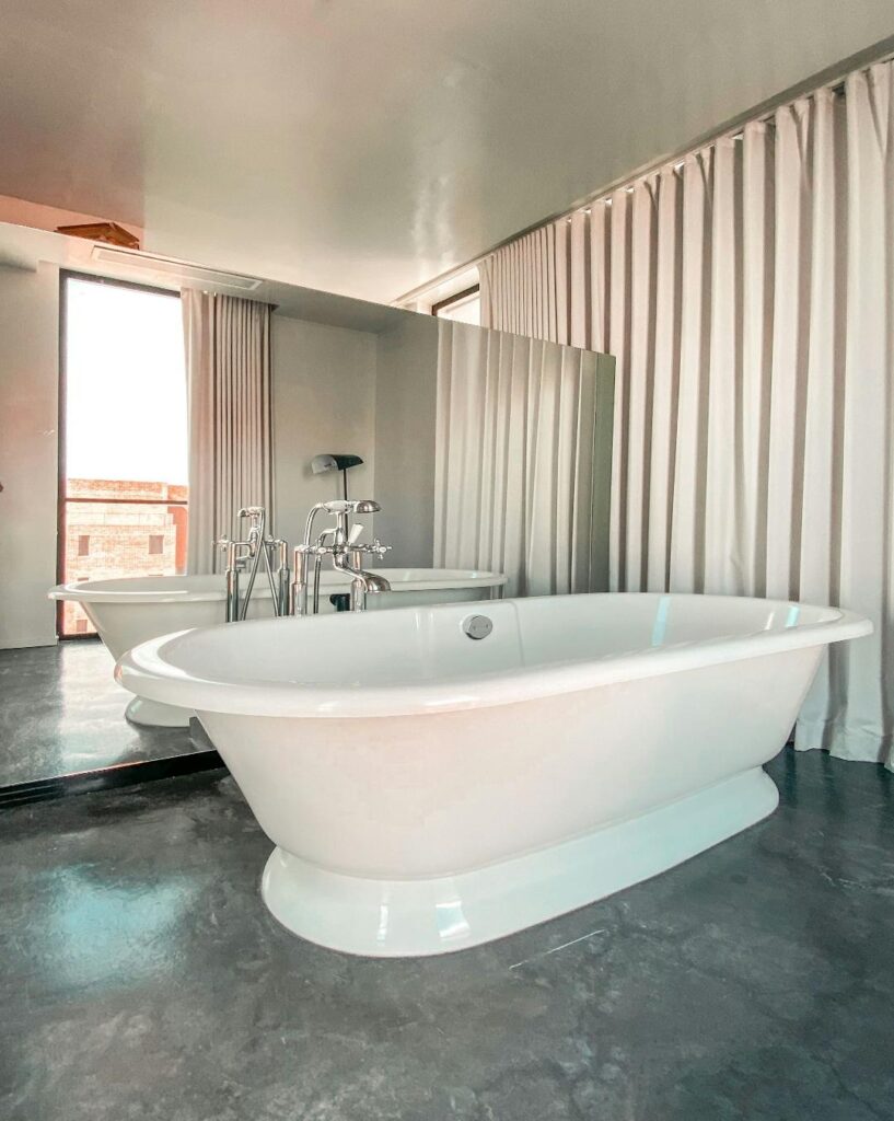 An image of a white bathtub with a mirror behind it depicting an out of frame window.