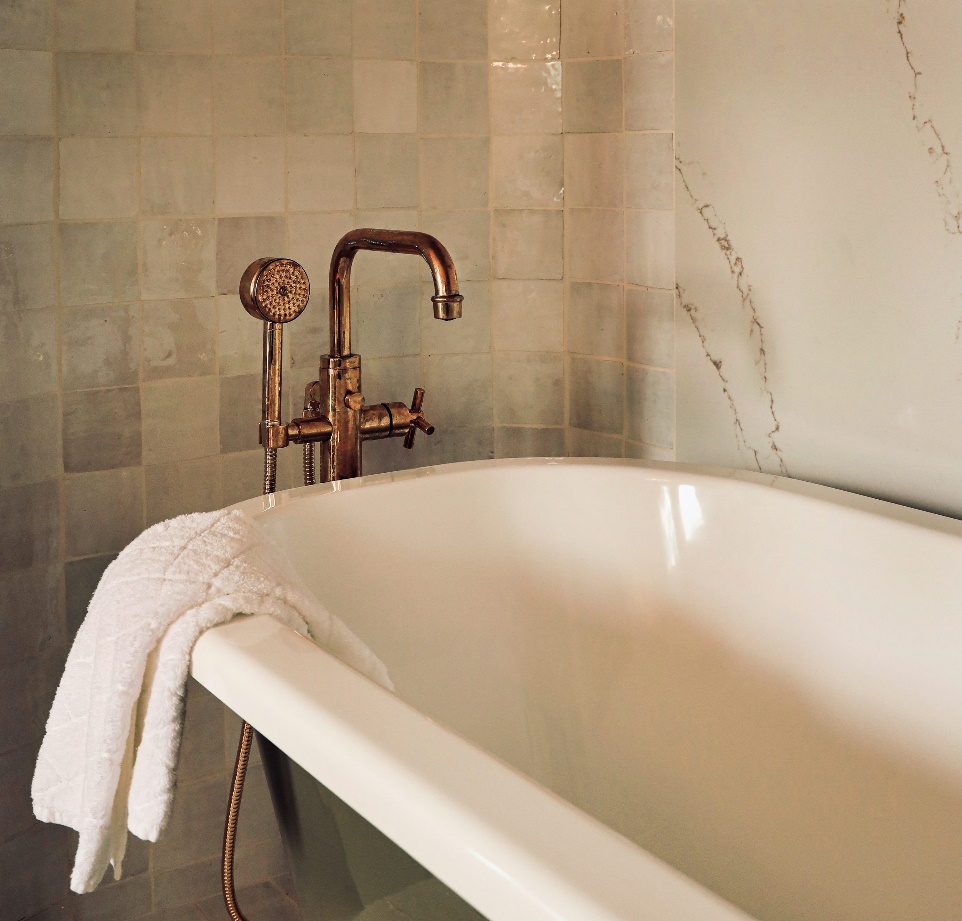 An image of a white bathtub with copper colored fixtures.