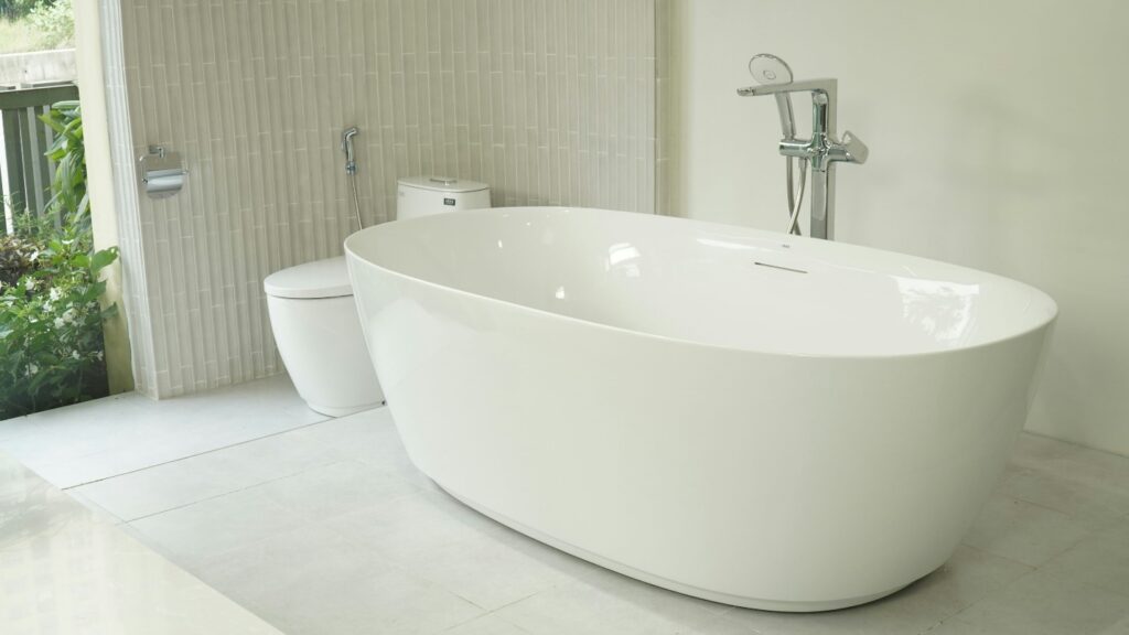 An image of a shiny, white bathtub in a neutral themed washroom.